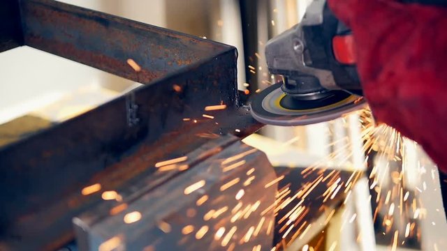 Grinding power tool in use, sparks. Close up. Slow motion.