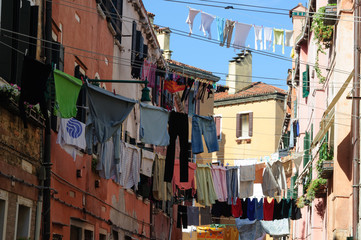 Fototapeta na wymiar Traditional Italian street with clothes hanging out to dry between old houses, somewhere in Venice.