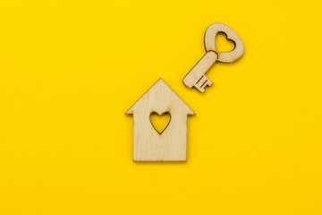 Symbol of a small house and a key with a heart on a yellow background.