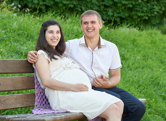 happy couple in summer city park outdoor, pregnant woman, bright sunny day and green grass, beautiful people portrait
