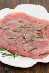 raw turkey with rosemary on white dish