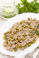 buckwheat with peas on white dish on wooden background