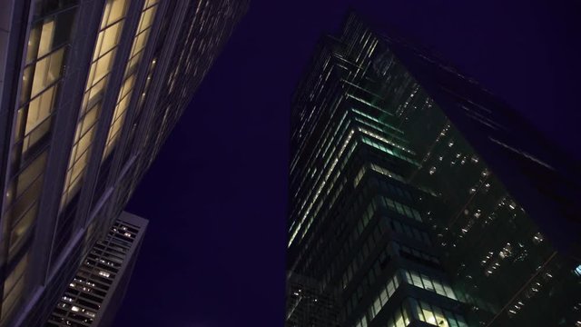 Looking up at full moon and towering skyscrapers at night