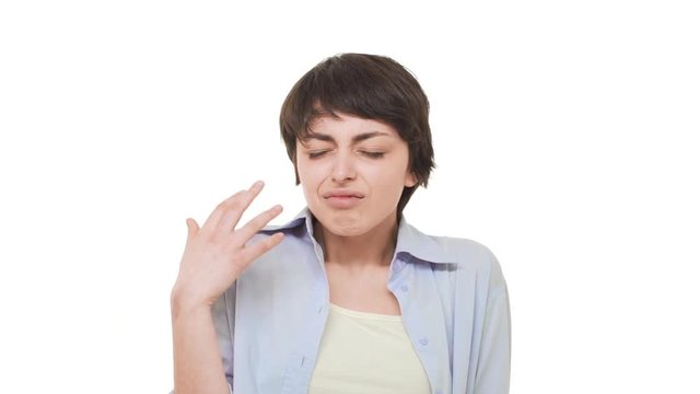 Young Caucasian female with short haircut wrinkling her face from four smell over white background in slowmotion