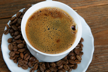 Cup with coffee on the table next to coffee beans