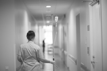 A nurse is carrying a tripod with a solution for infusion in the hospital.