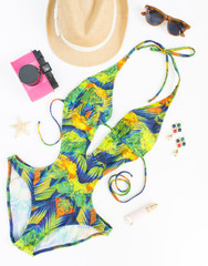 Summer outfit, beach outfit, summer stuff. Exotic pattern swimsuit, retro sunglasses, pink retro camera and straw hat. Flat lay, top view.