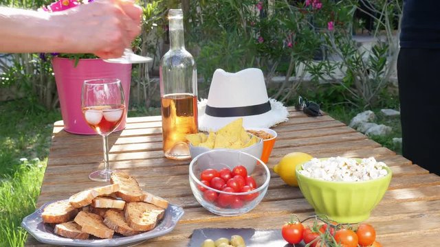 people cheering with glass of rosé wine in holiday summer brunch party table outdoor in a house backyard with appetizer and organic vegetables