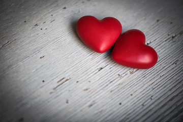 zwei rote Herzen auf grauem Holz