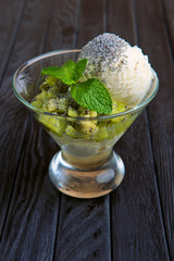 A cup of apple ice cream decorated with kiwi, mint leaves and poppy