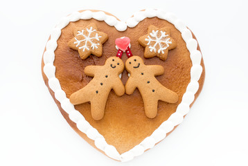 Close up of a cute Gingerbread heart decorated with Gingerbread Men and Gingerbread Stars on white background.
