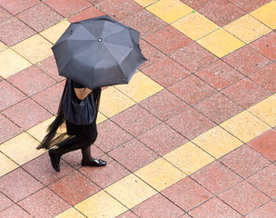 Girl with umbrella walking along paving stones