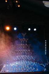 the pyramid of glasses with champagne on the wedding party. The smoke and light show. Background holiday themes - 158227200