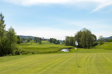 Fototapeta na wymiar Golf course. Hole with a white flag on a sunny day