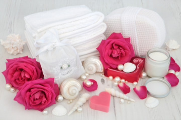 Obraz na płótnie Canvas Rose flowers with skincare beauty treatment products and cleansing ingredients with seashells and pearls on distressed white wood background.