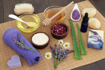 Medicinal herbs, flowers and ingredients for skincare with cleansing accessories on bamboo over oak...