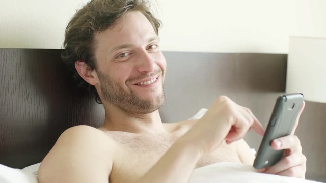 Man lying in bed looking at smart phone
