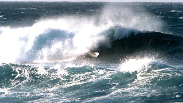 Surfer getting covered by a rough wave in super slow motion