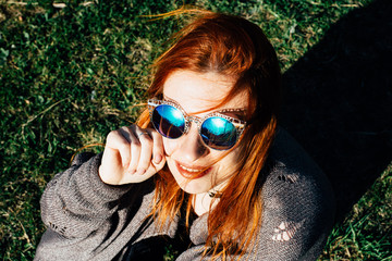 Portrait of a young redhead woman  in sunglasses outdoor in spring time