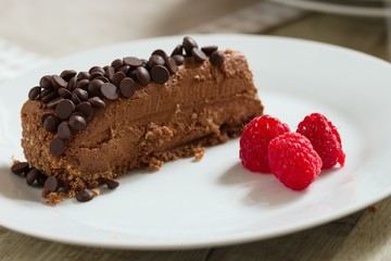 Nice serving of chocolate cheese cake decorated with choloate chips and raspberries
