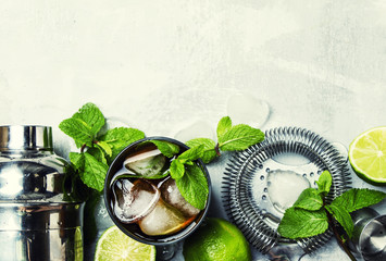 Alcoholic cocktail with rum, cola, ice and mint, bar tools, drink background, top view