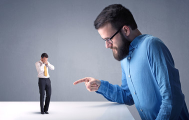 Young businessman fighting with miniature businessman