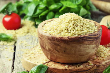 Bulgur in bowl, old wooden background, selective focus