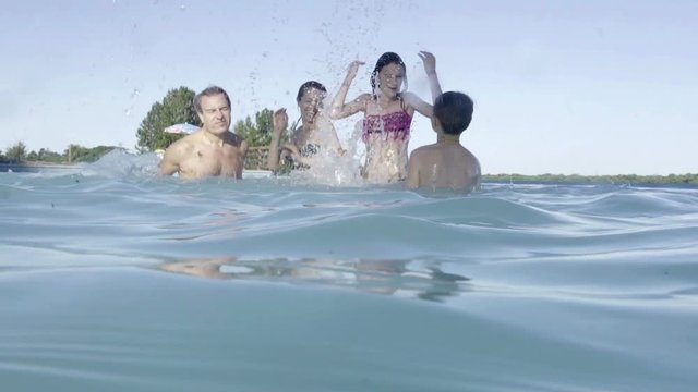 Family in swimming pool splashing each other