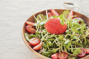 Sunflower sprouts and strawberries salad on wooden bowl