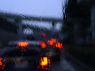 雨のフロントガラス越しのブレーキランプ