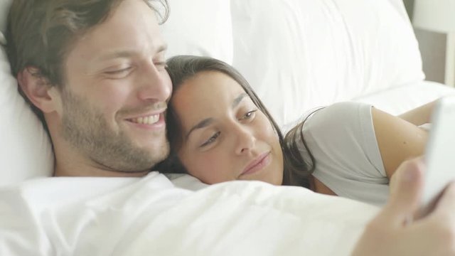 Couple using wireless device in bed