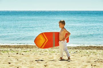 happy boy on the beach with a surfboard . The concept of summer vacation