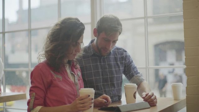 Couple using digital tablet together in coffee shop