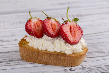 Sandwich of strawberry and cottage cheese on the wooden table, close up