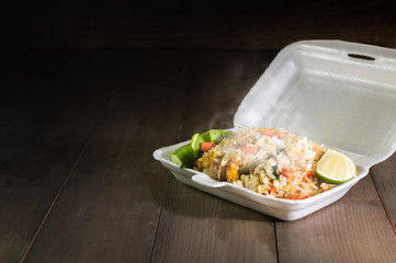 Hot food in foam box on wood table