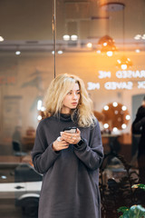 Blonde girl standing with smartphone