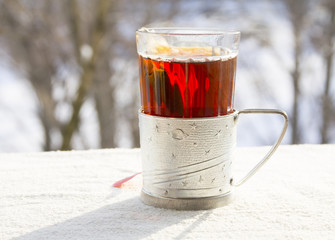 Hot tea in a faceted glass against the background of winter nature