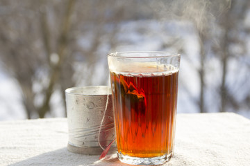 Hot tea in a faceted glass against the background of winter nature