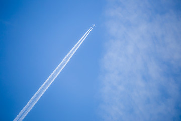 A plane with contrails in the deep blue sky
