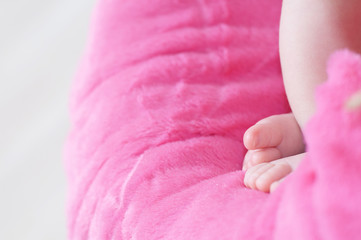 Newborn feet closeup, baby girl heels on pink background of mohair blanket, soft and cute