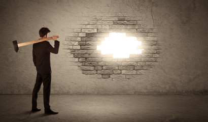 Business man hitting brick wall with hammer and opening a hole