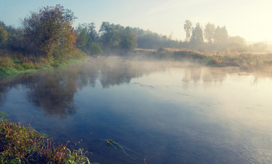 Fototapeta na wymiar Foggy autumn landscape with small river
