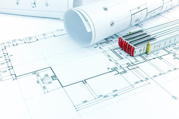 house plan, rolls of architectural blueprints and folding ruler on desk