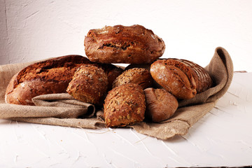 Different kinds of bread and bread rolls on board from above. Kitchen or bakery poster design.