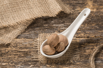 Porcelain spoon full of spices rests on old boards, rustic style