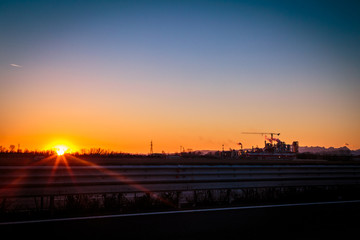 sun goes down behind an industry