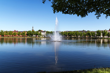 Fountain on the lake pfaffenteich in schwerin, the capital city of mecklenburg-vorpommern, germany, blue water with reflection and blue sky, copy space