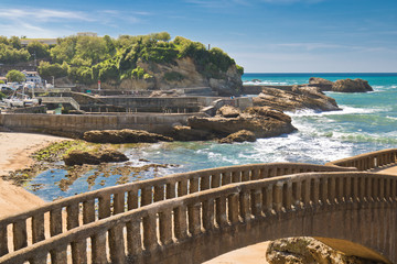 Beautiful stone walking footbridge over sandy beach in touristic destination surf spot with...