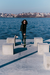 Pretty teen girl spending time in the park near the water with his skate