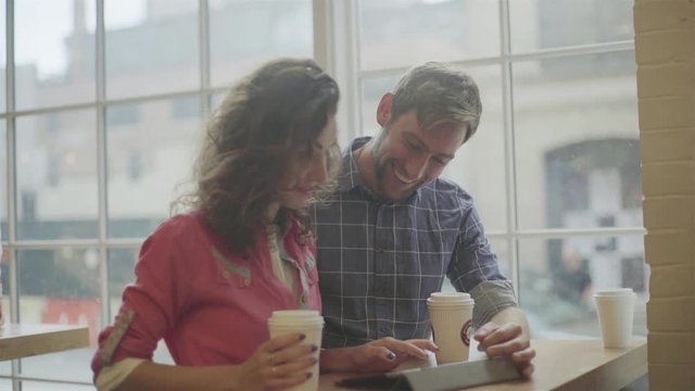 Couple using digital tablet together in coffee shop